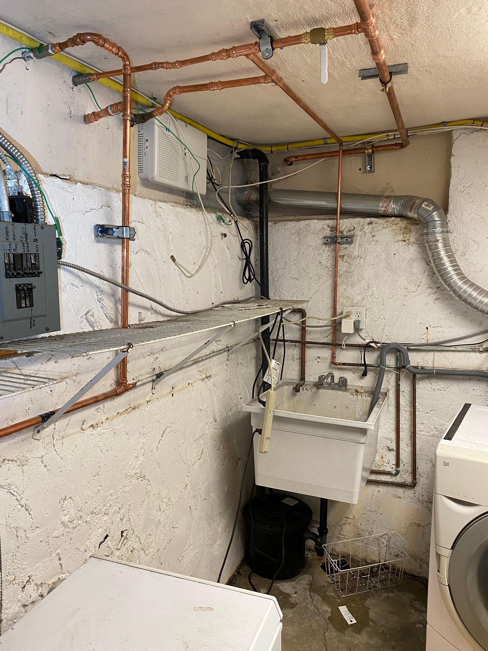 A laundry room with a sink , washer and dryer , and copper pipes.