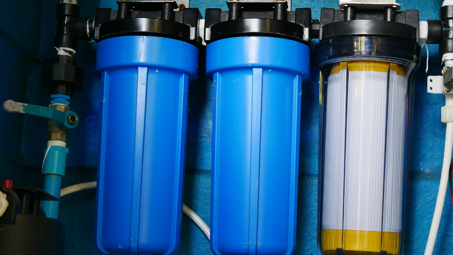 Three blue water filters are hanging on a wall.