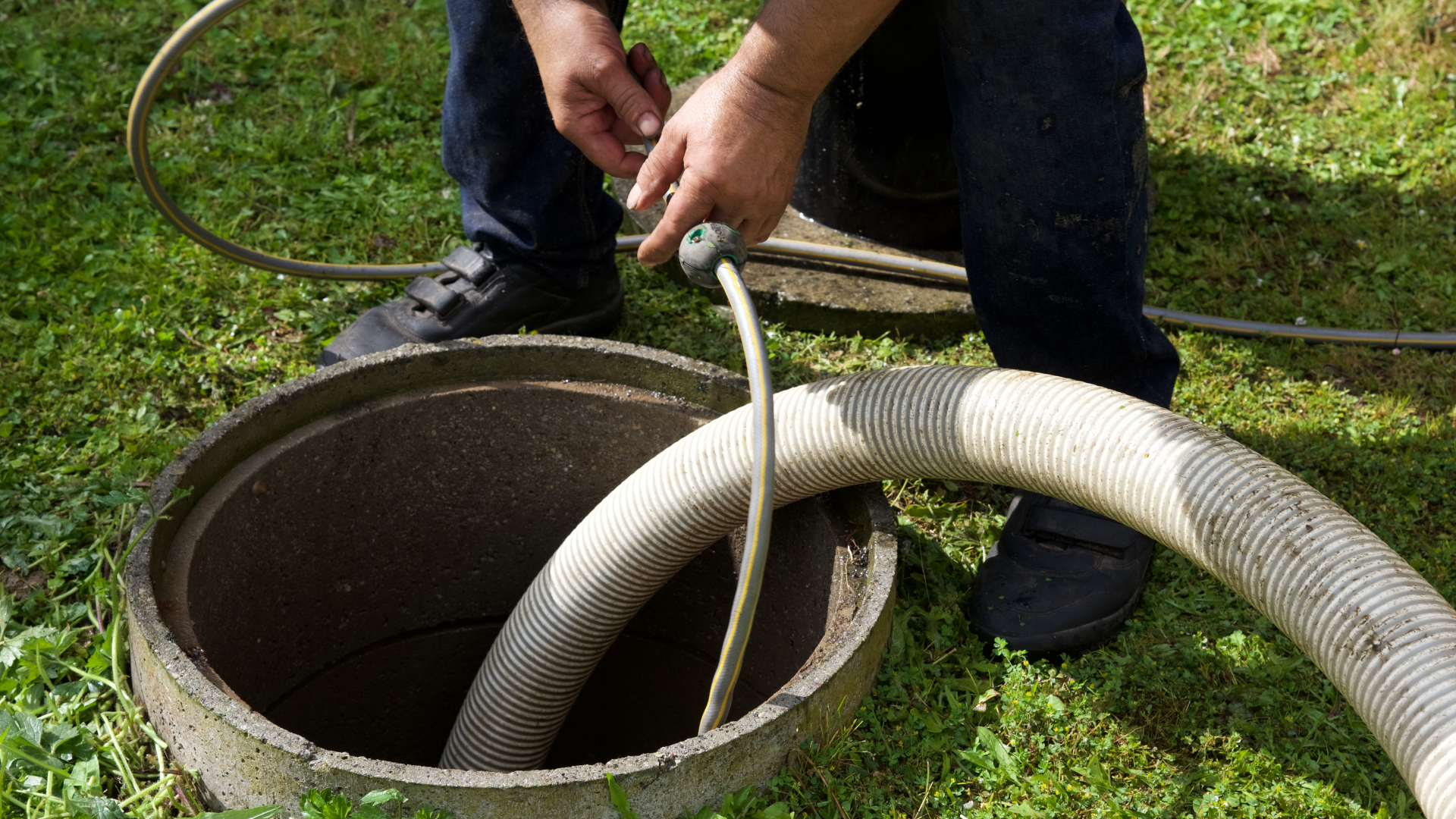 A man is pumping a hose into a septic tank.