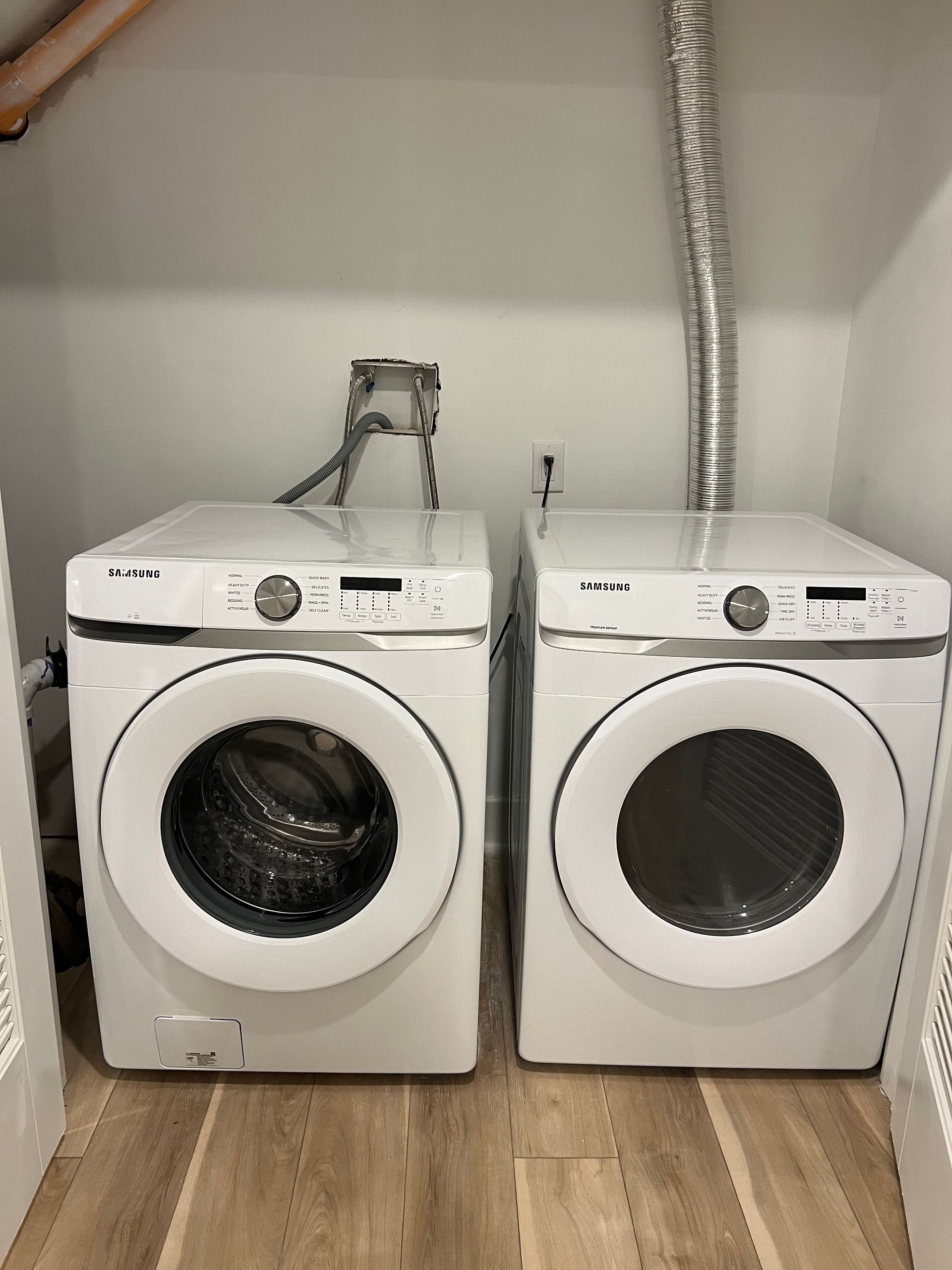 Two white washers and dryers are sitting next to each other in a laundry room.