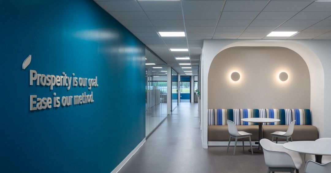 Hallway with blue accent wall, white ceiling lights, and seating area with curved archway and neutral tones.