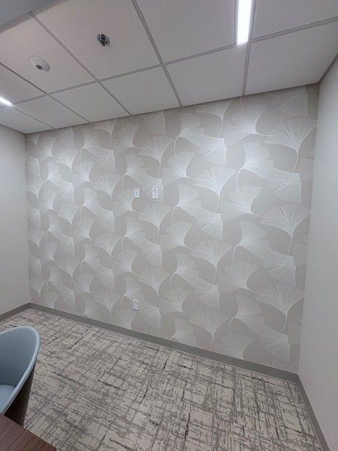 Room with patterned, light-colored wallpaper; neutral carpet; and drop ceiling.