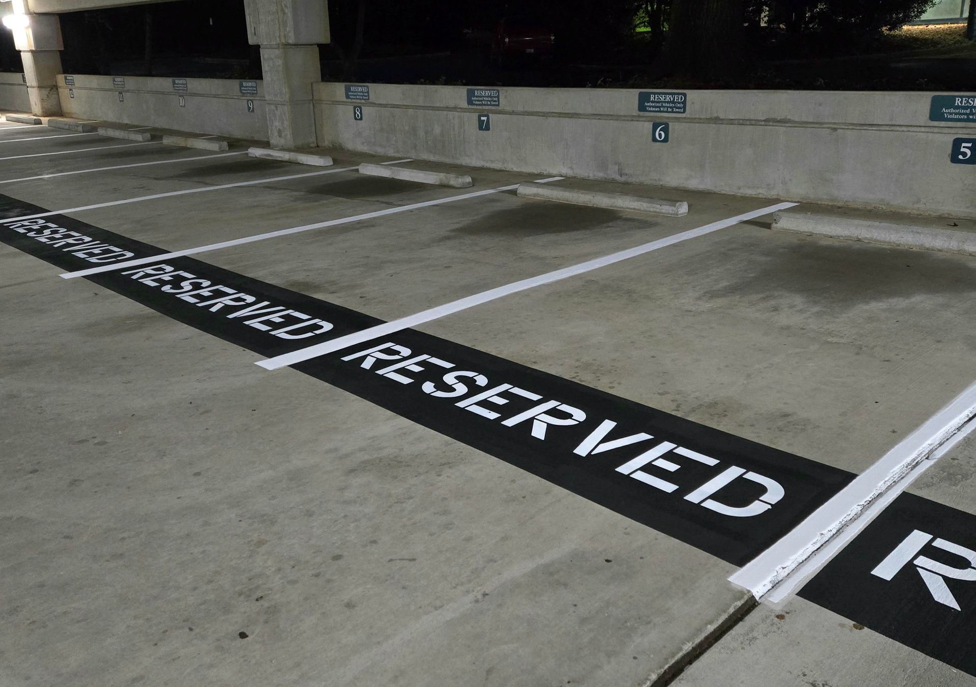 Reserved parking spaces in a concrete garage, black asphalt with white 