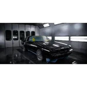 Black sports car in a glossy garage or paint booth, lit by overhead lights.