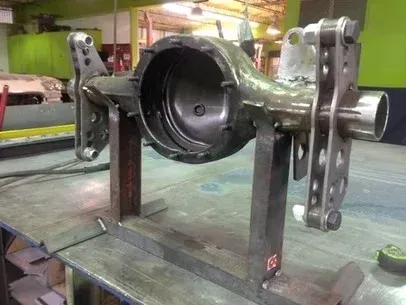 Metal mechanical assembly on a workbench, with a large central housing and perforated mounting plates.