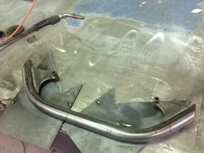 Bent metal tube on a scratched windshield, with a clamp and wires in the upper left.