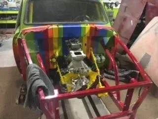 Rainbow-painted car frame with exposed engine and front end under repair or construction