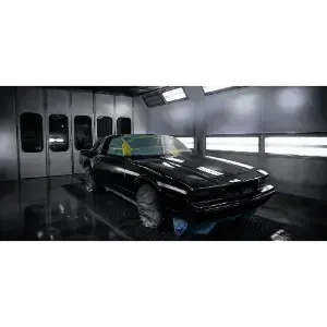 Black sports car in a glossy garage or paint booth, lit by overhead lights.