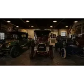 Three vintage cars parked indoors in a dimly lit garage display
