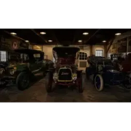 Three vintage cars parked indoors in a dimly lit garage display