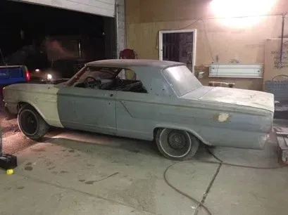 Classic gray convertible car parked in a garage at night, viewed from the side.