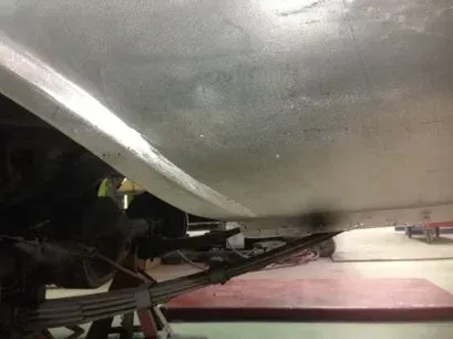 Under a car, close-up of metal underside and suspension parts on a lift