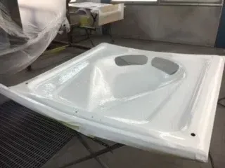 White bathtub insert with built-in headrest sitting on a metal worktable in a workshop