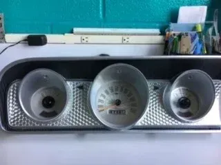 Three round speakers on a shelf, with a central silver speaker and two smaller black speakers on either side.