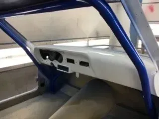 Blue roll cage inside a stripped car interior with a white dashboard and bare floor