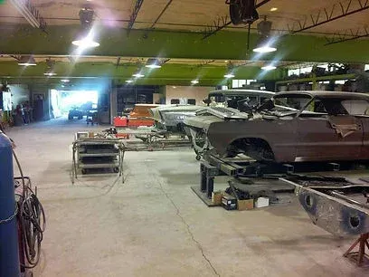 Auto body shop with several cars on lifts and tools in a large garage