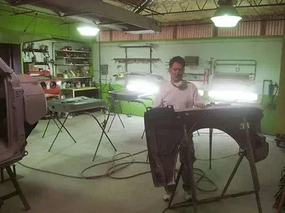 Person standing beside a keyboard in a dim workshop with shelves, cables, and lights in the background