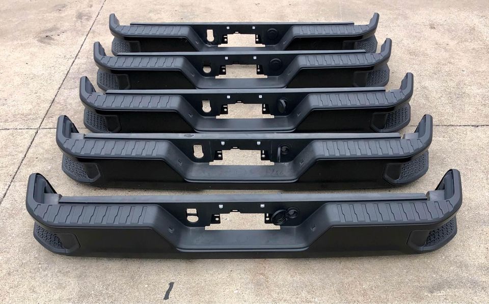A bunch of black bumpers are stacked on top of each other on the ground.