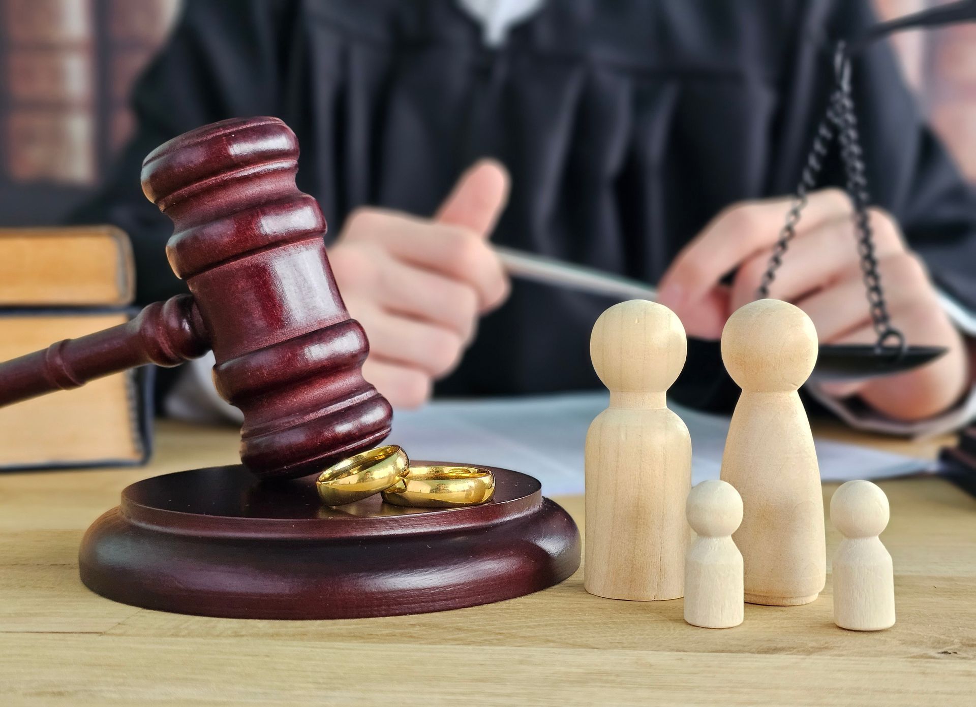 Small wooden figurines of parents and children, and a judge on a courtroom table. Small wooden figurines of parents and children, and a judge on a courtroom table.