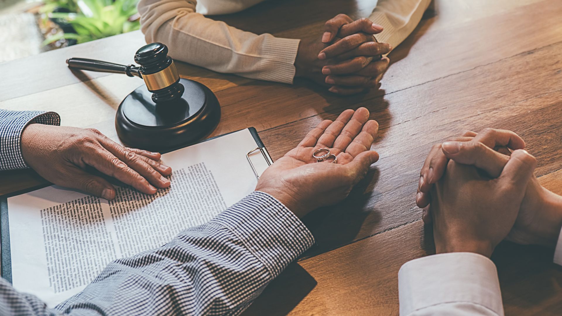 Divorce lawyers meeting with couple at desk reviewing legal papers and gavel during consultation.
