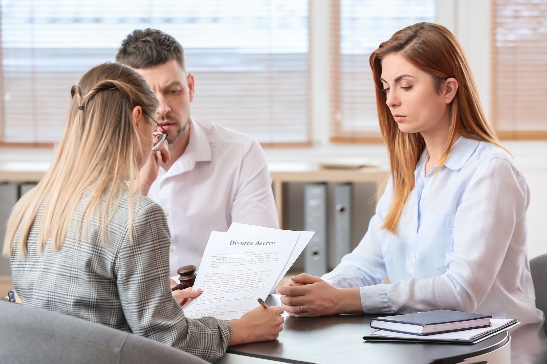 A divorce attorney is reviewing legal documents with a couple during private mediation.