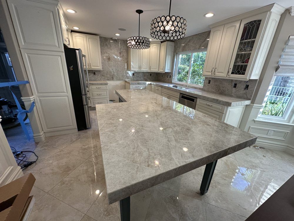 Bright modern kitchen with a large marble island, white cabinets, and pendant lights