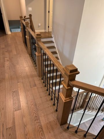 Stairwell with wooden railing and black iron balusters along an upstairs hallway