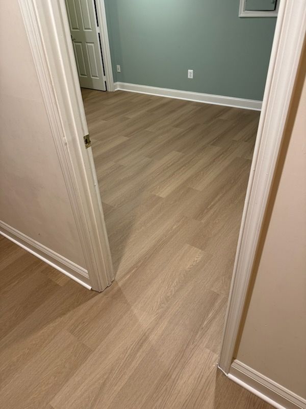 Empty hallway with light wood flooring, white trim, and a teal wall in an adjacent room.