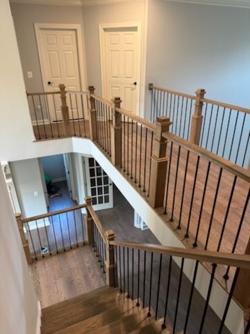 Interior stair landing with wooden railing, white walls, and two closed doors