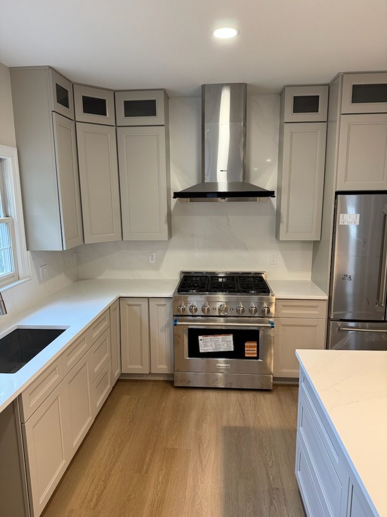 Bright modern kitchen with white cabinets, stainless steel appliances, and wood floors