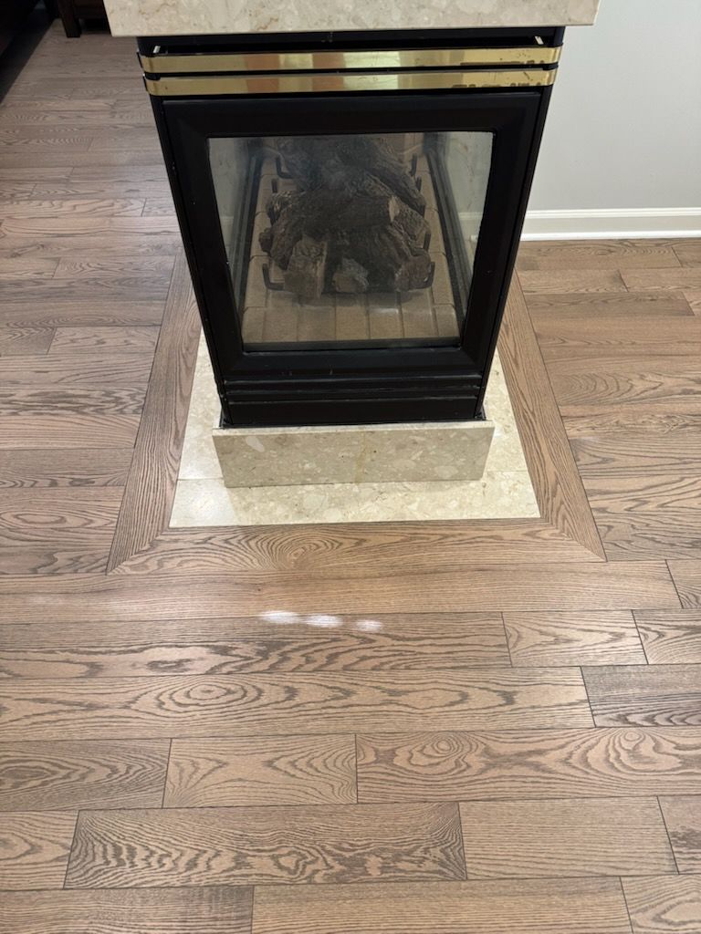 Black fireplace with glass doors on a stone hearth over hardwood floor.