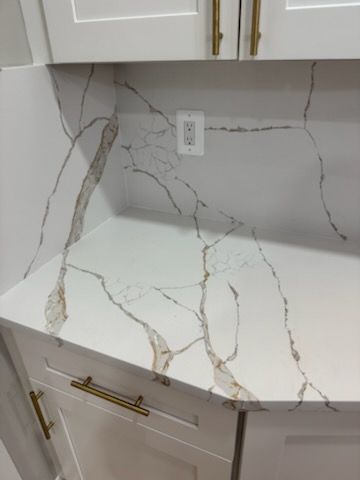 White quartz kitchen countertop with gold veining and matching marble-look backsplash.