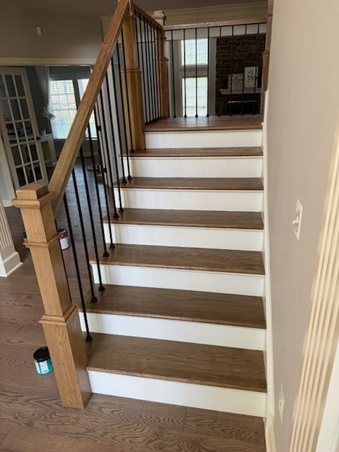 Wooden staircase with white risers and black railing in a hallway