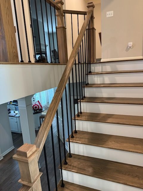 Wooden staircase with black iron balusters and white risers in a beige home interior