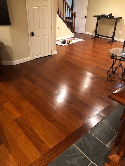 Empty living room with glossy hardwood floors, white closet doors, staircase, and a small table by the wall