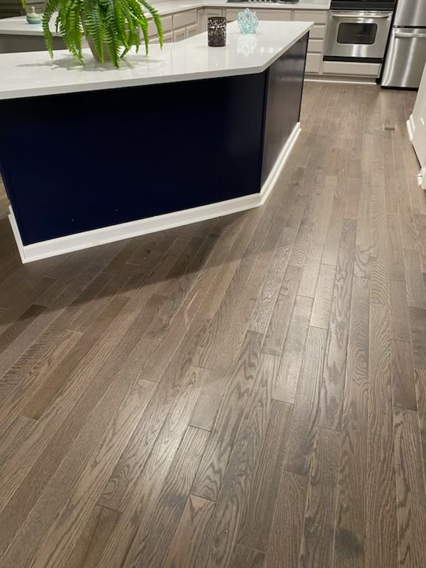 Modern kitchen with dark blue island and light wood flooring, viewed from the hallway