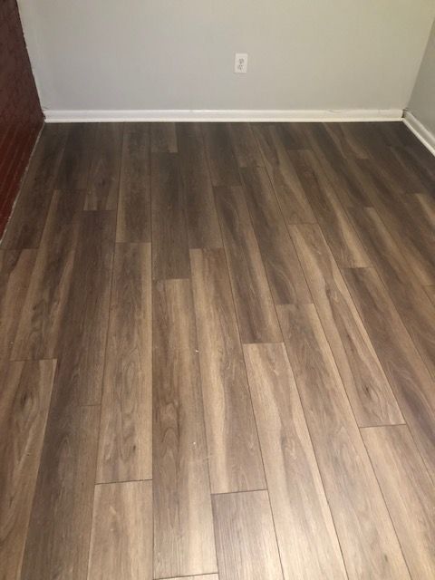 Empty room with wood-look laminate flooring and white walls.