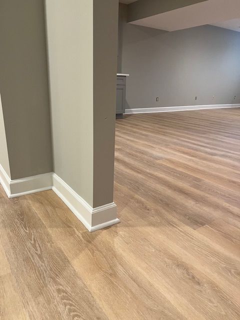 Empty room with gray walls, white baseboards, and light wood flooring