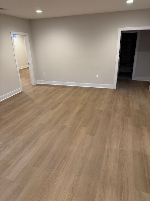 Empty room with wood floors, light gray walls, and two open doorways.