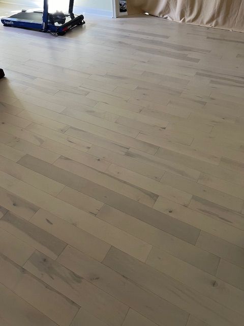 Light wood floor being installed, with tools visible in the upper left corner.