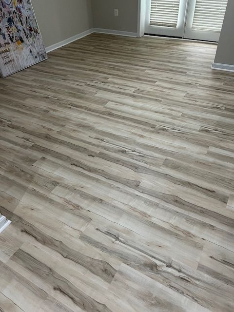 Empty room with light wood laminate flooring and neutral walls.