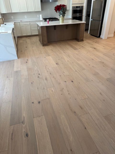 Bright kitchen with light wood floors, white cabinets, and a dark island with flowers on top