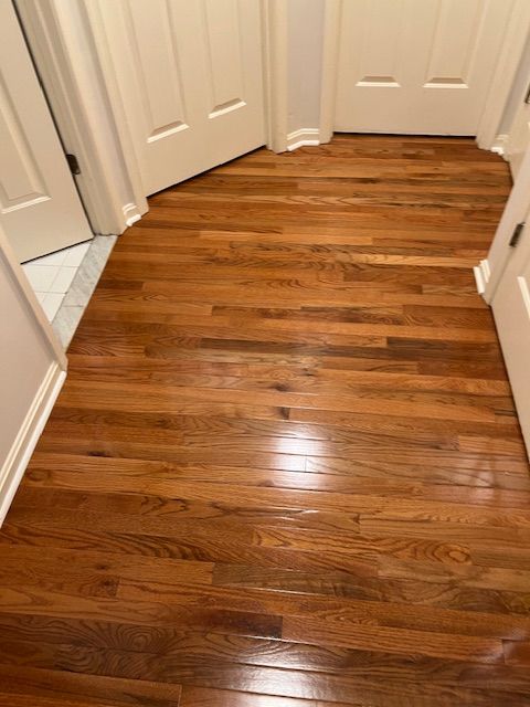 Shiny hardwood hallway floor with white doors and walls