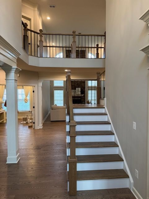 Interior foyer with staircase, hardwood floors, and upstairs balcony railing