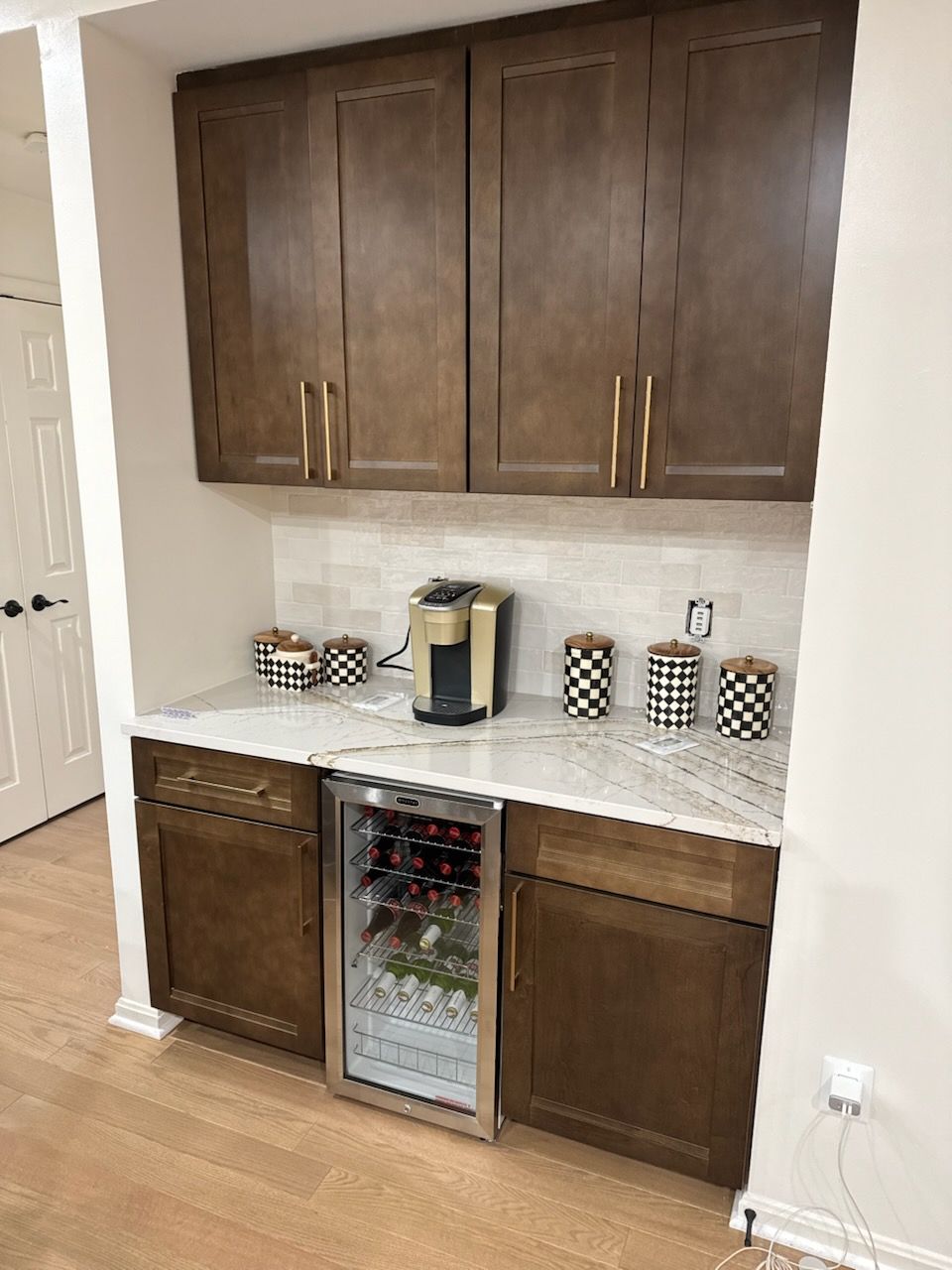 Kitchen cabinet beverage station with coffee maker and mini wine fridge beneath dark wood cabinets