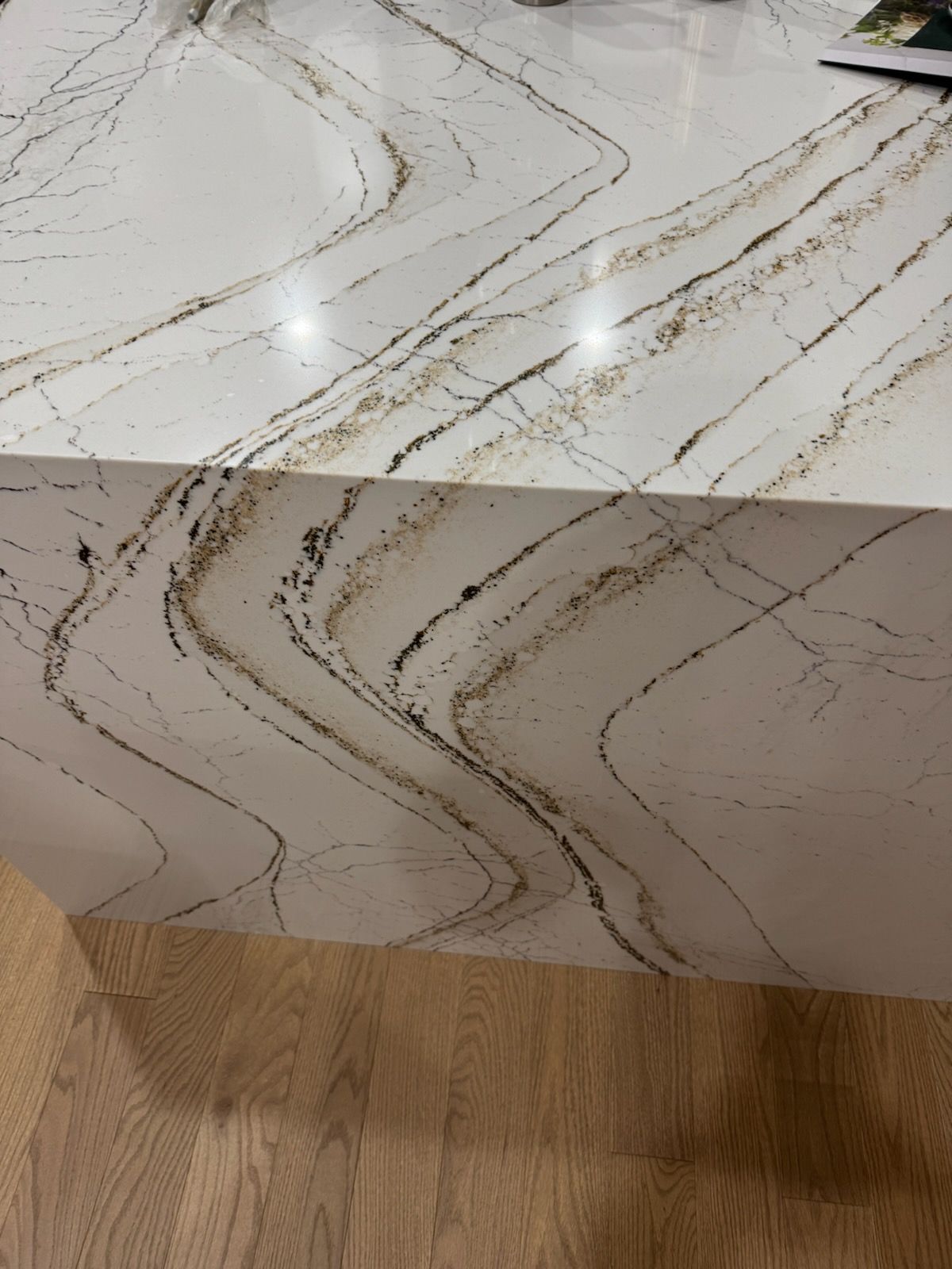 White marble-look countertop with gold veining above a light wood floor.