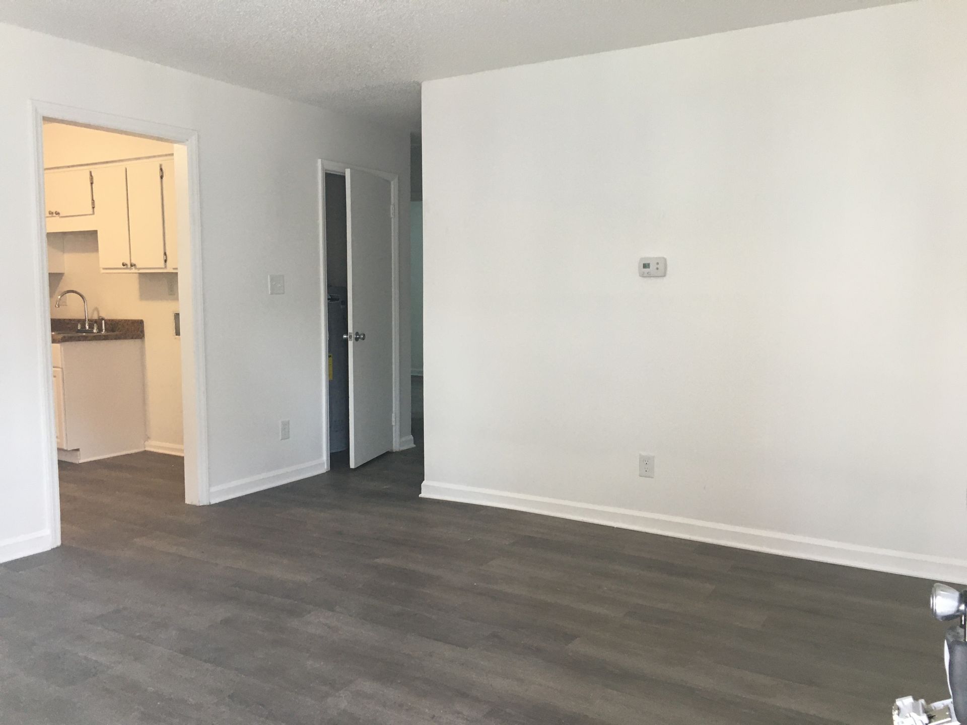 An empty living room with hardwood floors and white walls.