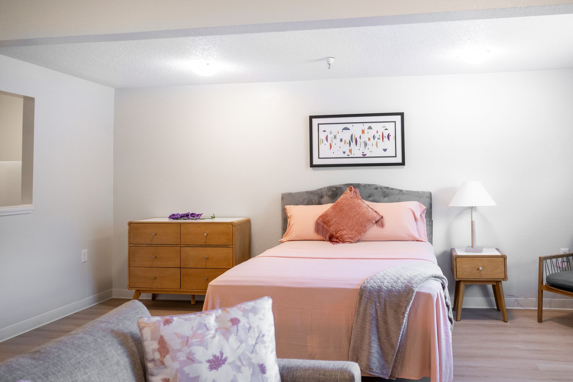 A bedroom with a bed , couch , nightstand and dresser.