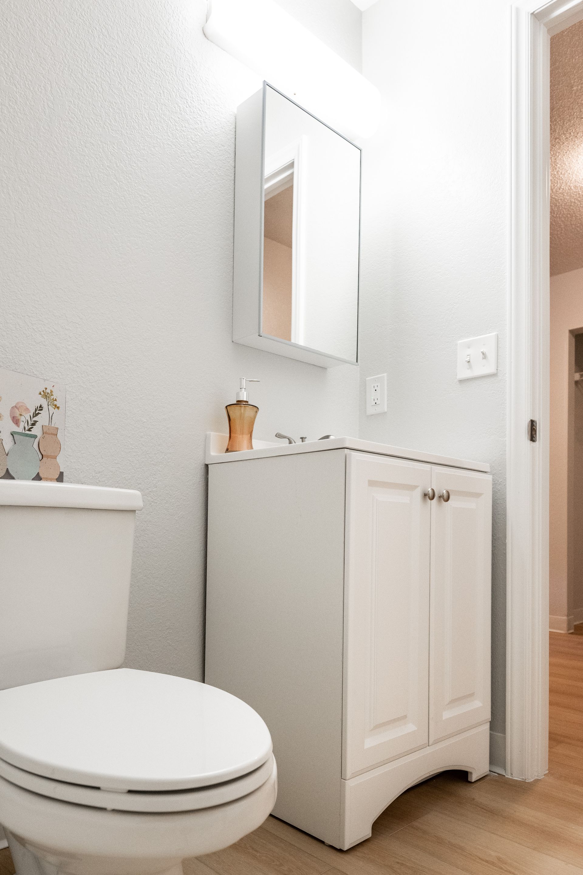 A bathroom with a toilet , sink and mirror