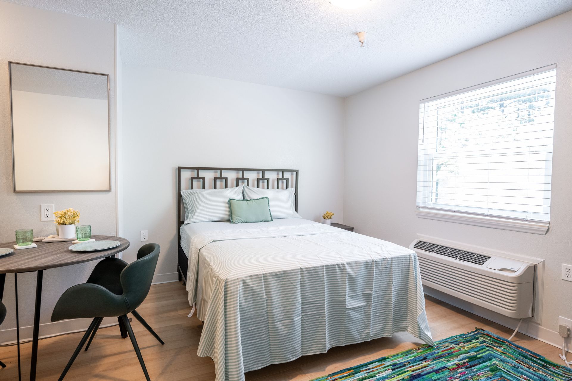 A bedroom with a large bed , a table and chairs.